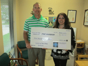 Dr. Bryan Kestler of Accident & Injury Center, presents a check to The Harbor