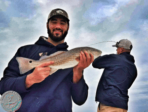 Brandon Workman, pitcher for the Boston Red Sox and World Series Champion, showing off a solid Redfish with his guest, Brandon Loy, “bowed-up” in the background,.