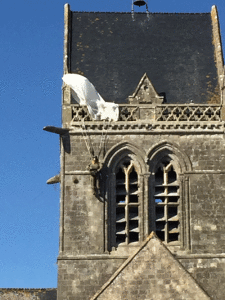 The church in Sainte-Mère-Église, a dummy paratrooper hangs from the church steeple commemorating the story of John Steele, who was an 82nd Airborne Paratrooper whose parachute got hung up on the church the morning of D-Day. 