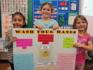 Kindergarten students in Ms. Peters Port O’Connor class conducted a science experiment to understand more about germs. They concluded that washing hands with warm soapy water does kill germs. In photo: Kailey Guzman, Enola Walton, Lexi Ruddick 
