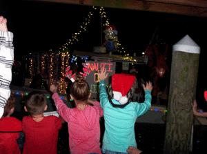 Excited children wave at passing boats, hoping to catch some candy and beads. Froggie’s Bait Dock was packed with folks watching the Lighted Boat Parade.
