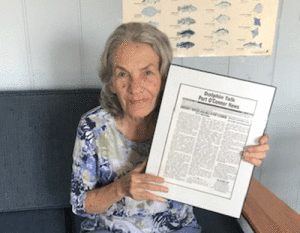 Editor Joyce Rhyne holds a framed copy of the first issue of Dolphin Talk.