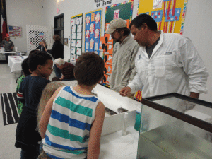 Texas Parks and Wildlife workers Dave Ushakow and Patrick Ragusin assist in the fish touch station for the book “One Fish Two Fish” and retired teacher Liz Bell reads to a group of Kindergartners.