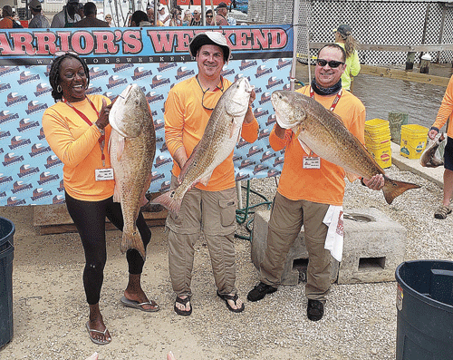 Veterans at Warrior’s Weekend show off their fish caught in Port O’Connor Waters. The red drum on the left was the largest catch of the day, weighing in at 33 pounds. -Photo by Mike Hessong