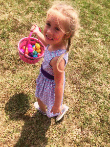   Miss Skylar Thumann gathers a basketful of colored eggs the Easter Bunny left on Easter weekend.