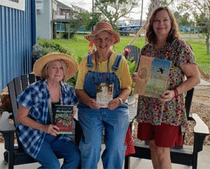 The book club’s September hostesses Nancy Ladshaw, Mary Ann Claiborne, and Darla Miles (not pictured is Brenda Berger) show off their copies of To Kill A Mockingbird. 