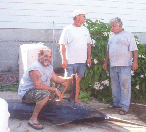 August, 2008: Justo Chavana ‘rides’ a shark as Freddie Harborth and Mike Gonzales prepare to help cut it up for food for the needy. Fisherman’s Chapel and friends still glean fish from most all fishing tournaments held here