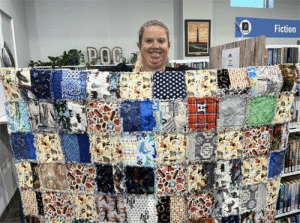 Assistant Librarian Margaret Claiborne shows one of the quilts donated to the POC Library by Edna Payne.