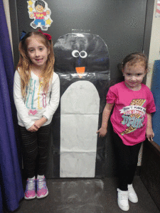  Ms. Peters’ POC Kindergarten class compared themselves to the actual size of an adult emperor penguin using the vocabulary taller, shorter or the same height. Left to right-Skyla Thumann and McKinley Dufner.