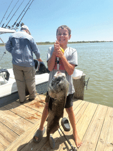 My 13 year old grandson, Oliver Thorpe,  caught a giant black drum… The drum is called big ugly and is about 55-60 pounds. And lives at Froggies Bait Dock. -Gail Martin