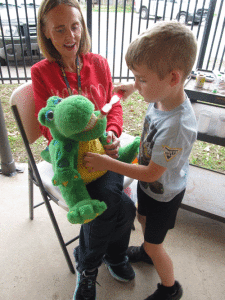 Dental Health District nurse, Shari Dierlam, lets Dean Bell practice brushing teeth on Alli the Alligator at Port O'Connor Kindergarten. 