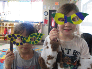 Bobbie Smith and Adalynn McCabe show off their Mardi Gras masks in Ms. Peters POC Kindergarten.